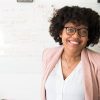 pexels-photo-1181519-1181519 Smiling businesswoman with glasses and afro hairstyle in an office setting.
